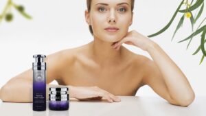 Woman model looking at camera with highend skincare products on surface