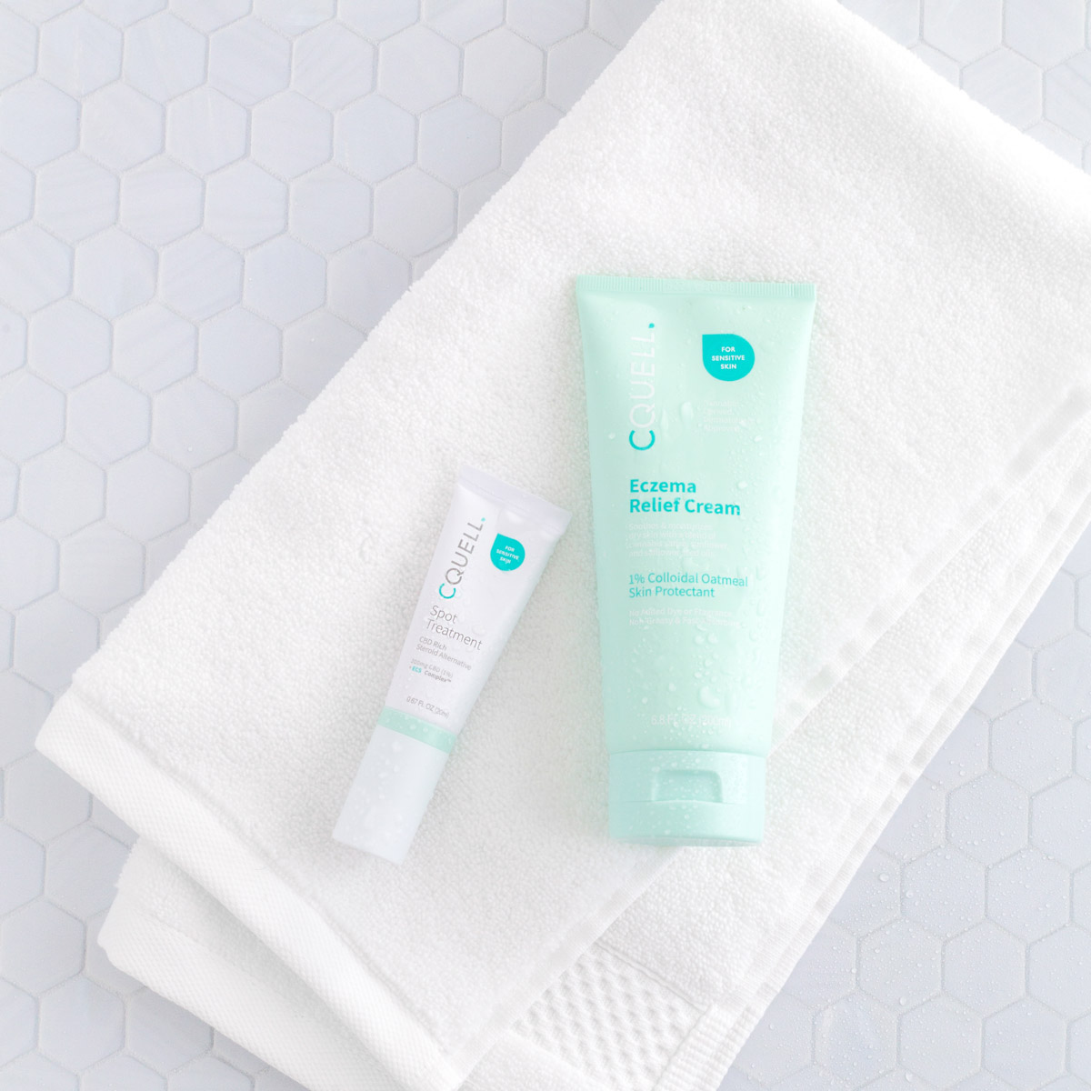 White and mint green skincare tubes laying on a white towel