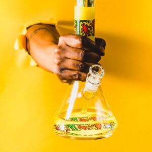 Person holding bong through yellow wall